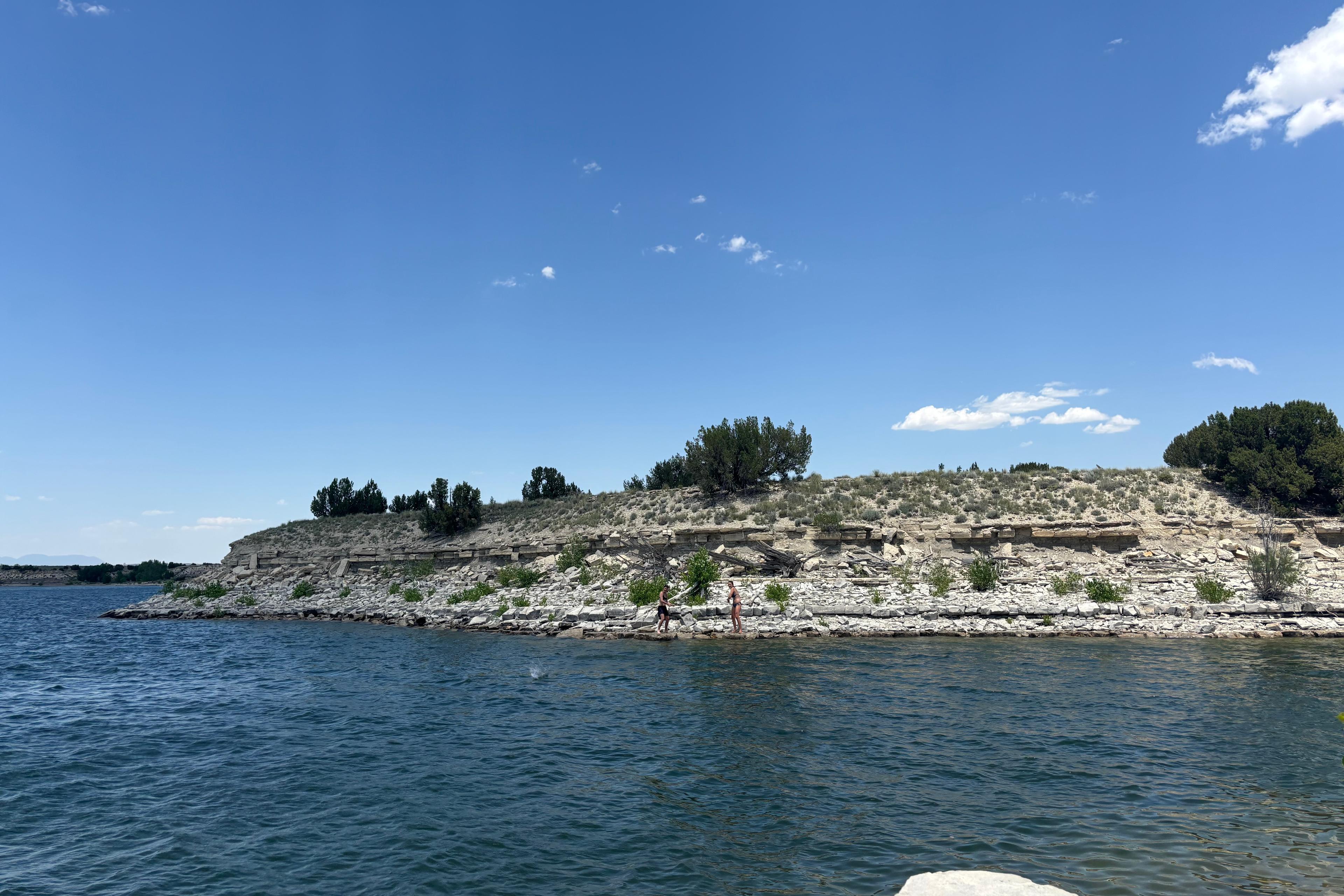 Two people skipping rocks across the water at Lake Pueblo.