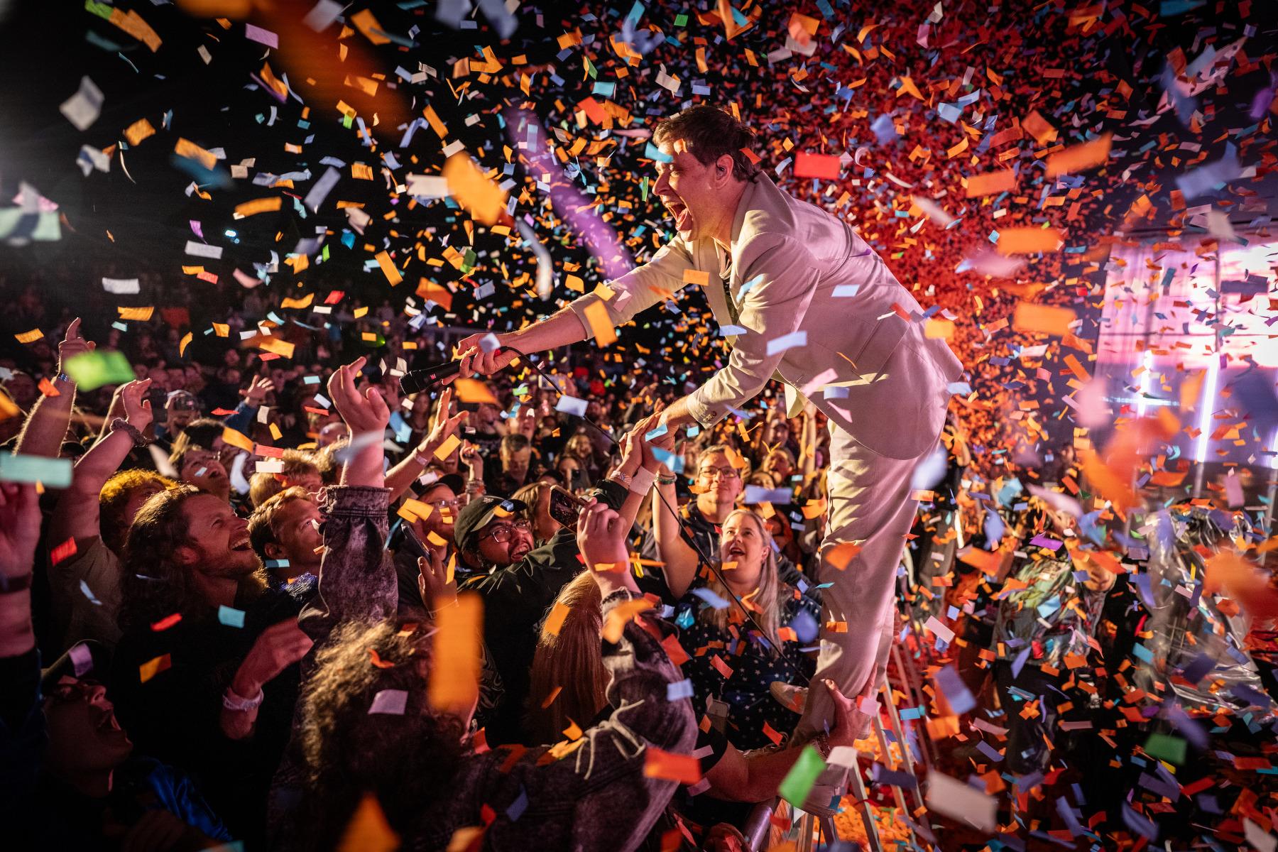 OK Go’s Damian Kulash stands atop the stage barricade and greets fans as confetti rains down at Indieverse