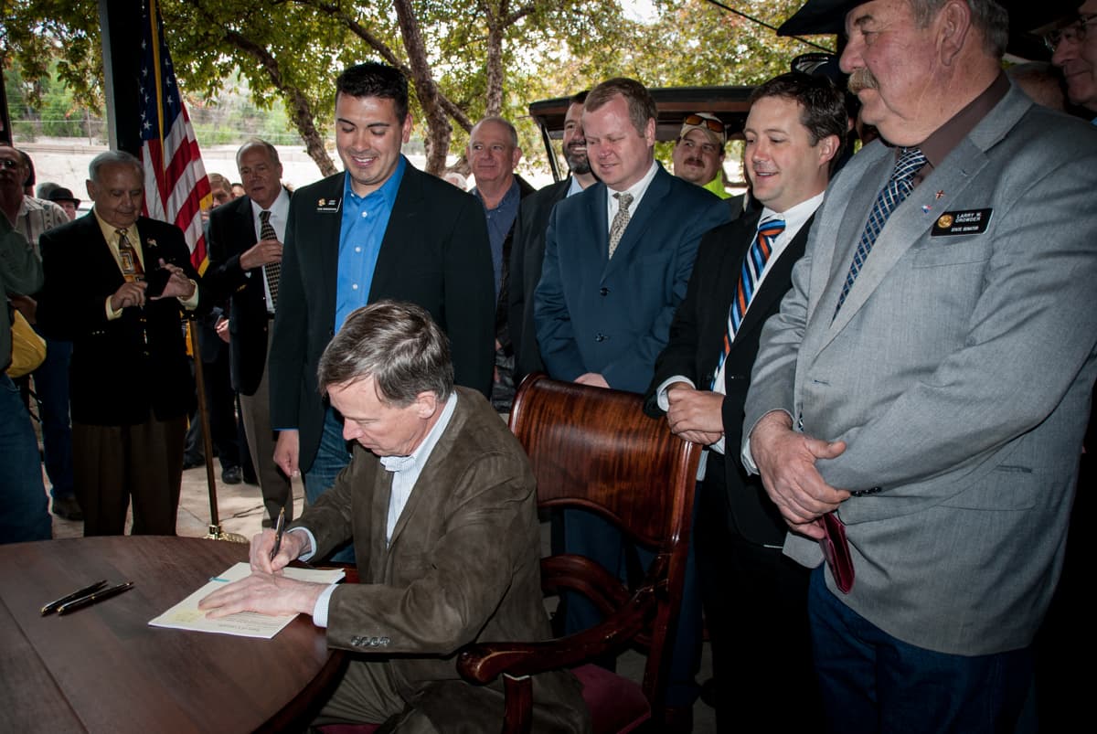 Governor John Hickenlooper signs a bill that creates a commission aimed at preserving and expanding Amtrak's Southwest Chief passenger rail service in Southern Colorado. Standing behind him are State Rep. Leroy Garcia (D-Pueblo), Amtrak's Ray Lang, Pueblo County Commissioner Sal Pace and State Senator Larry Crowder (R-Alamosa).