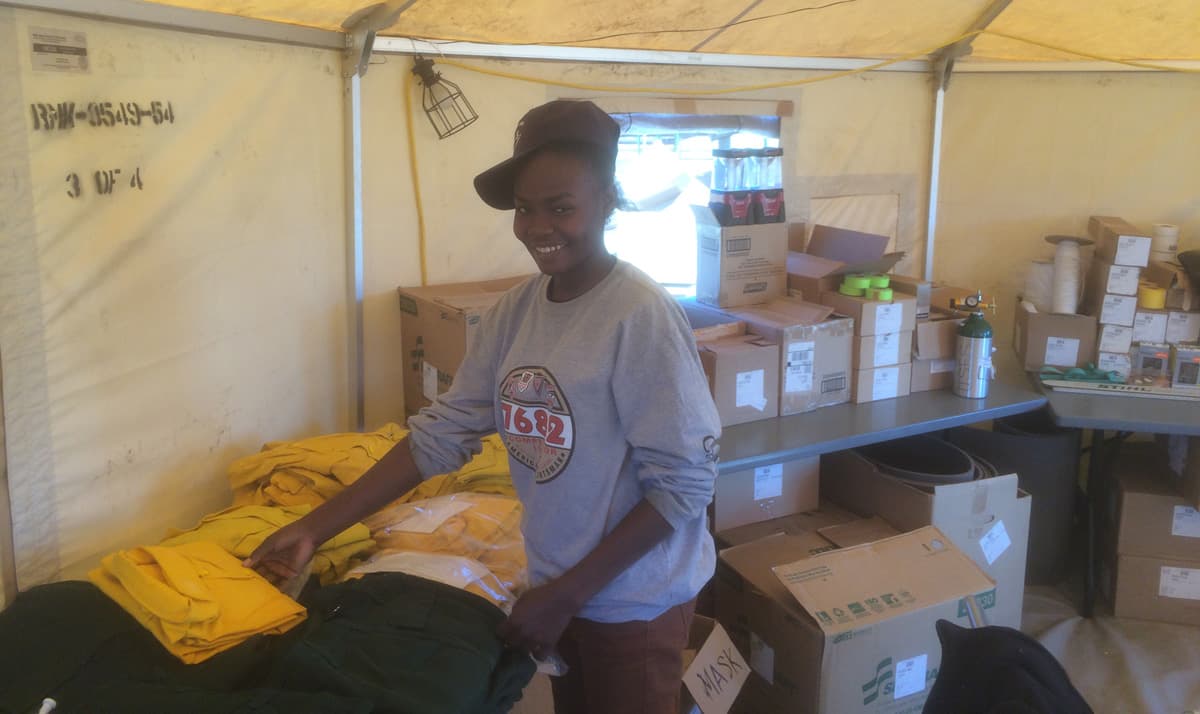 Nasim Abakar, a 19-year-old student originally from Sudan, works in the supply tent at the Hayden Pass Fire base camp.