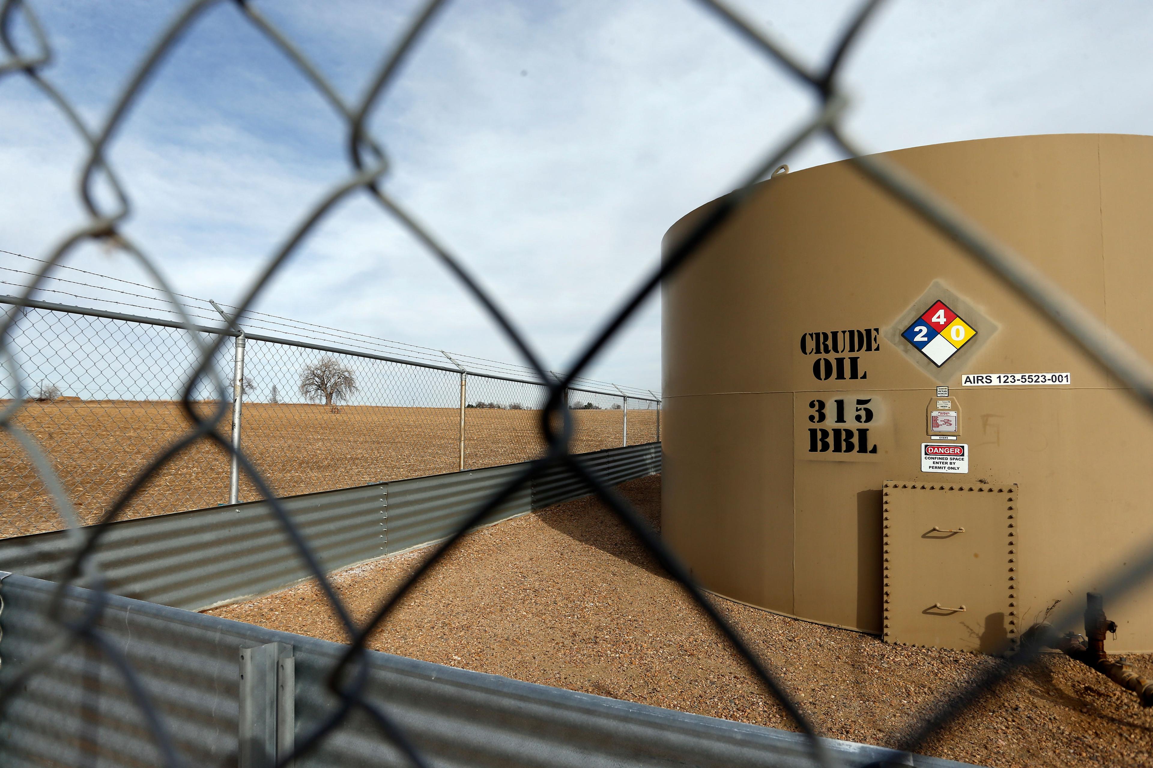 A crude oil storage tank sits behind a fence at a petroleum extraction site, in Weld County, near Mead, Colo., Monday, Feb. 13, 2017.
