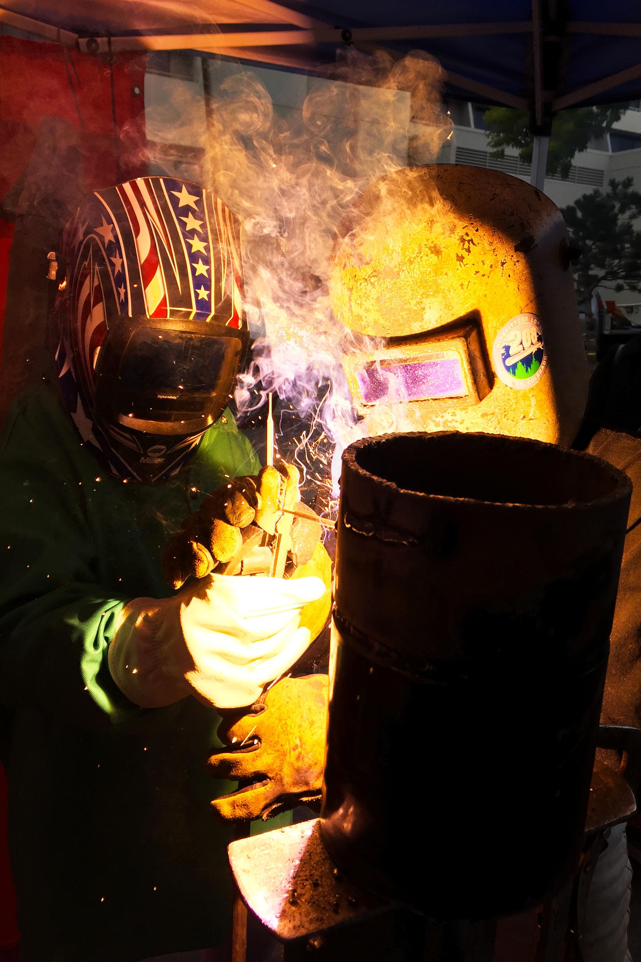 Photo: Pipefitting instruction 3 | An apprentice shows a young girl how to weld at a transportation and construction career fair - Natalia V. Navarro