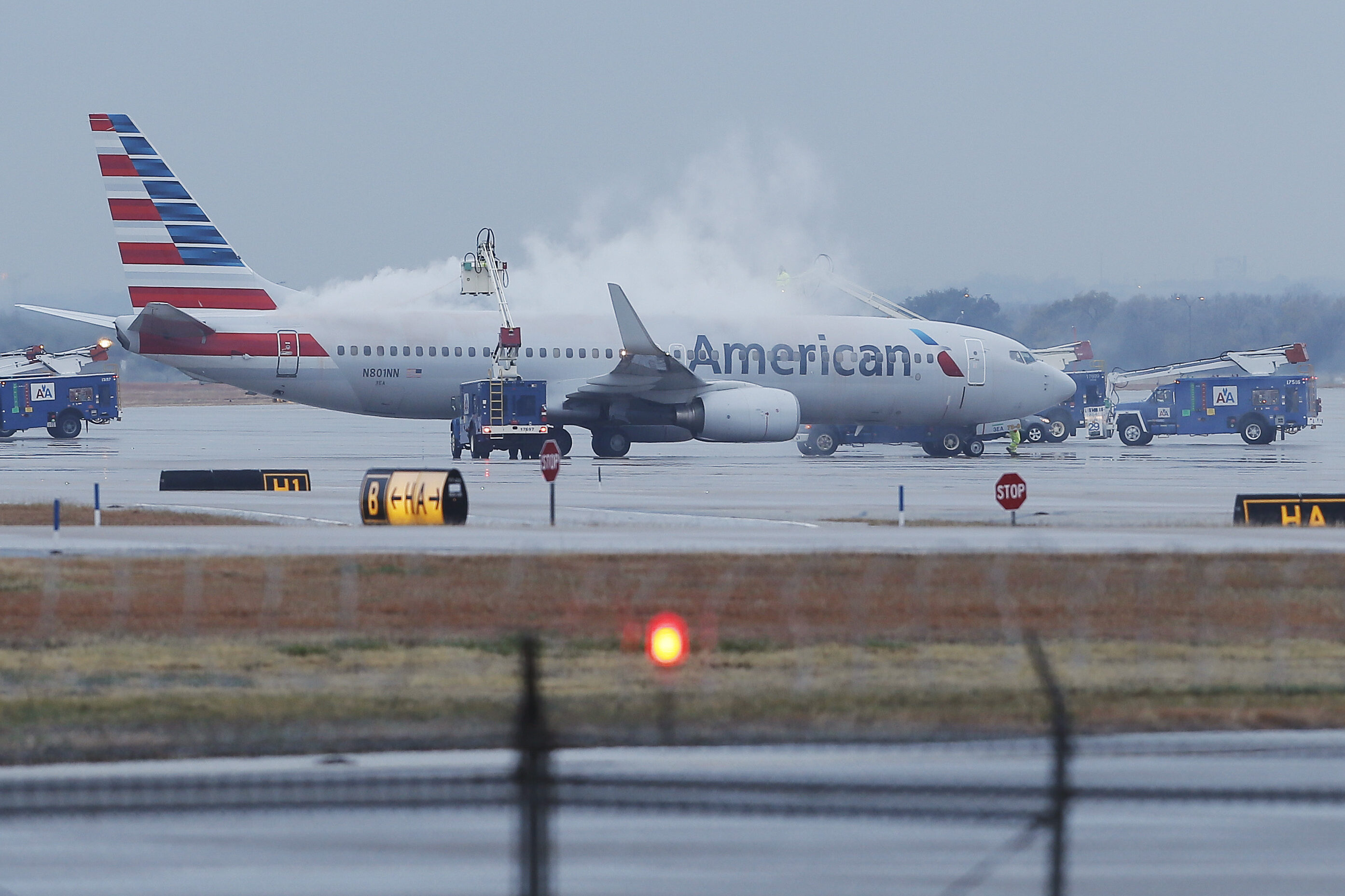 An American Airlines plane with white smoke rising from it.