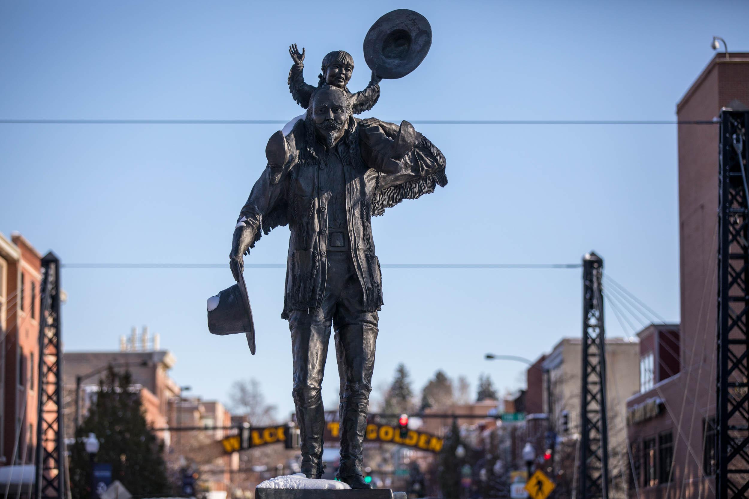 A statue of a boy on a man's shoulders stands in downtown Golden, Colorado.