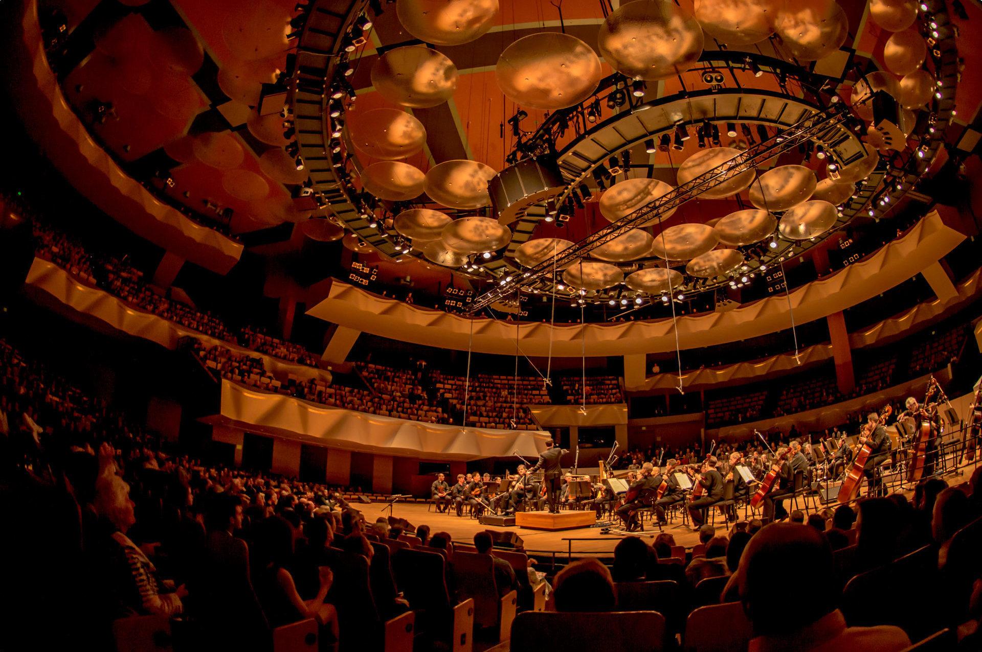 Boettcher Concert Hall lights dimmed, with full audience and symphony on stage