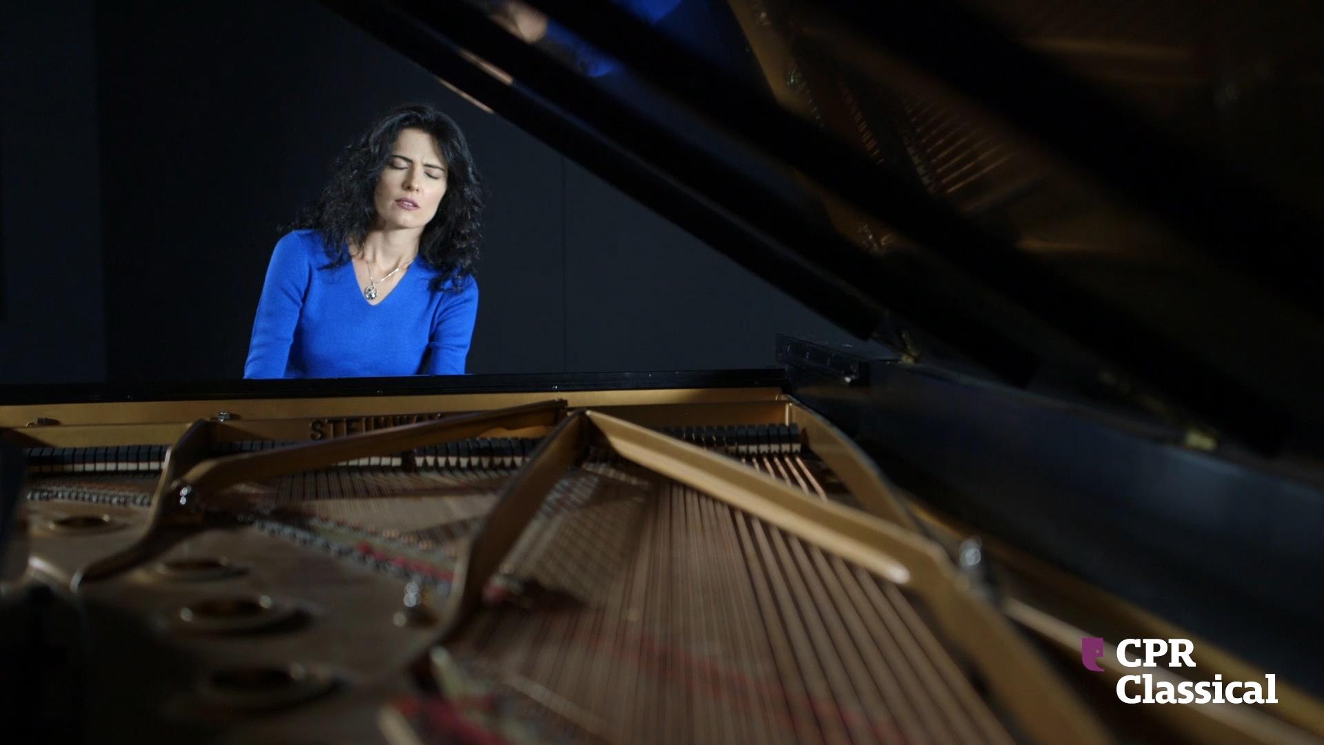 Katie Mahan sits playing the piano with eyes closed