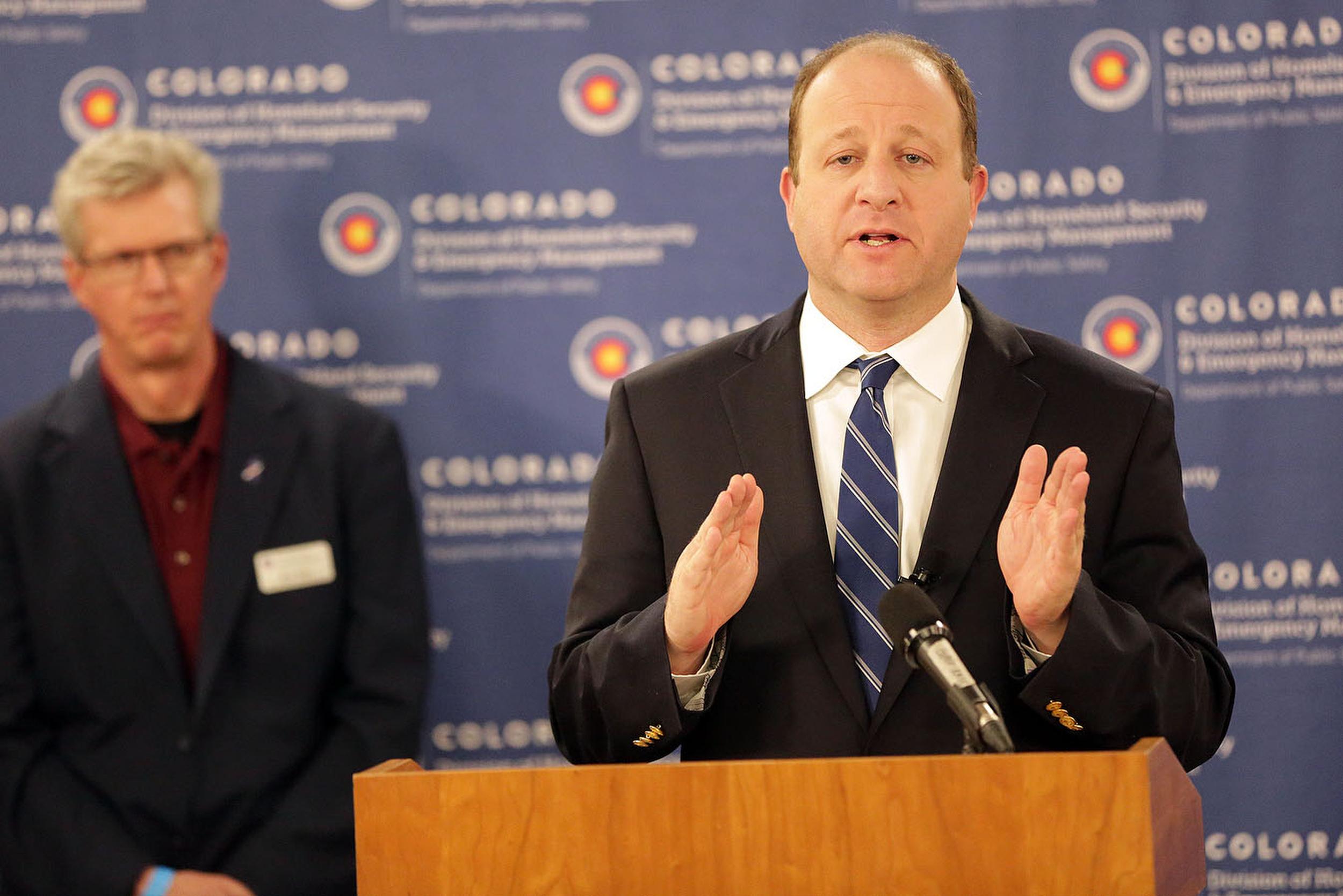 Colorado Gov. Jared Polis gestures during a press conference on March 25