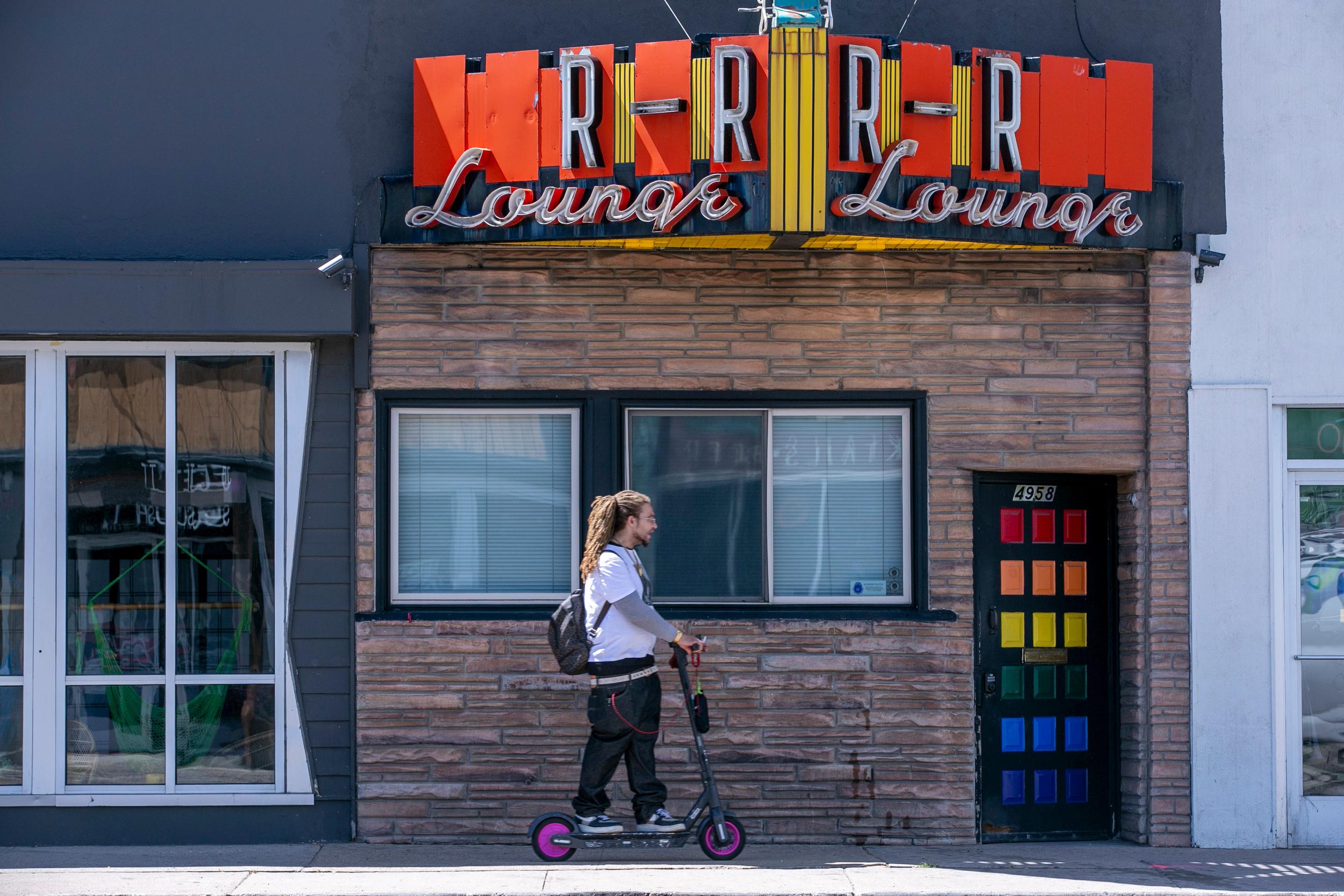 Scooter Rides Past R-R Bar On Colfax