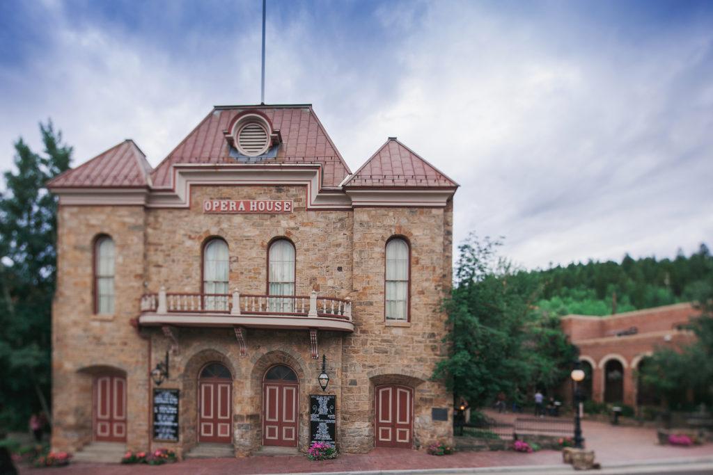 Central City Opera House, front view of the building during daytime with white whispy clouds on a blue sky