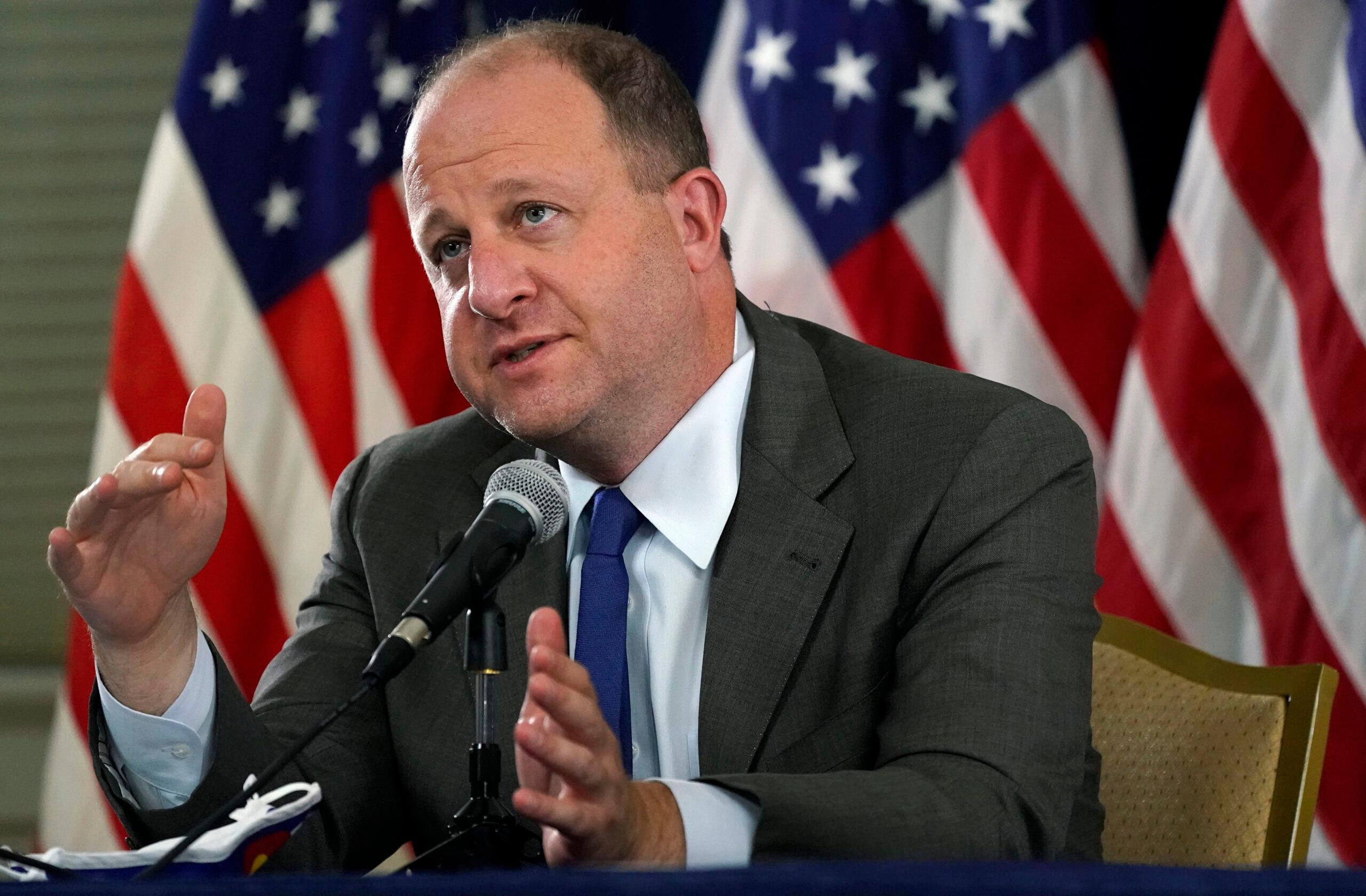 Governor Jared Polis makes a point during a news conference.