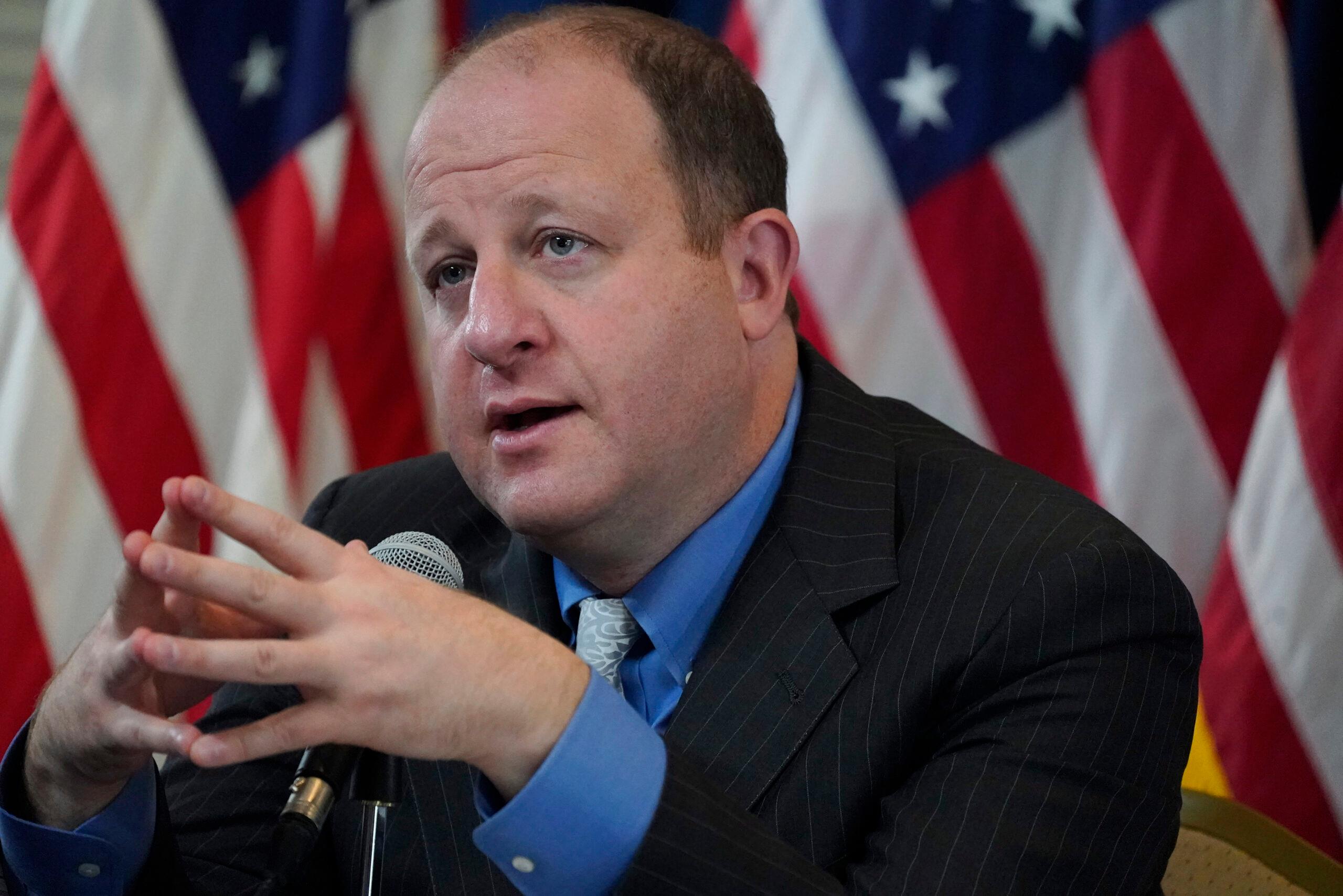 Jared Polis considers a question during a news conference.