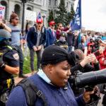 Iris Butler attempts to lead chants among supporters of Joe Biden as state police stand between them and supporters of Donald Trump at the Capitol. Nov. 7, 2020.