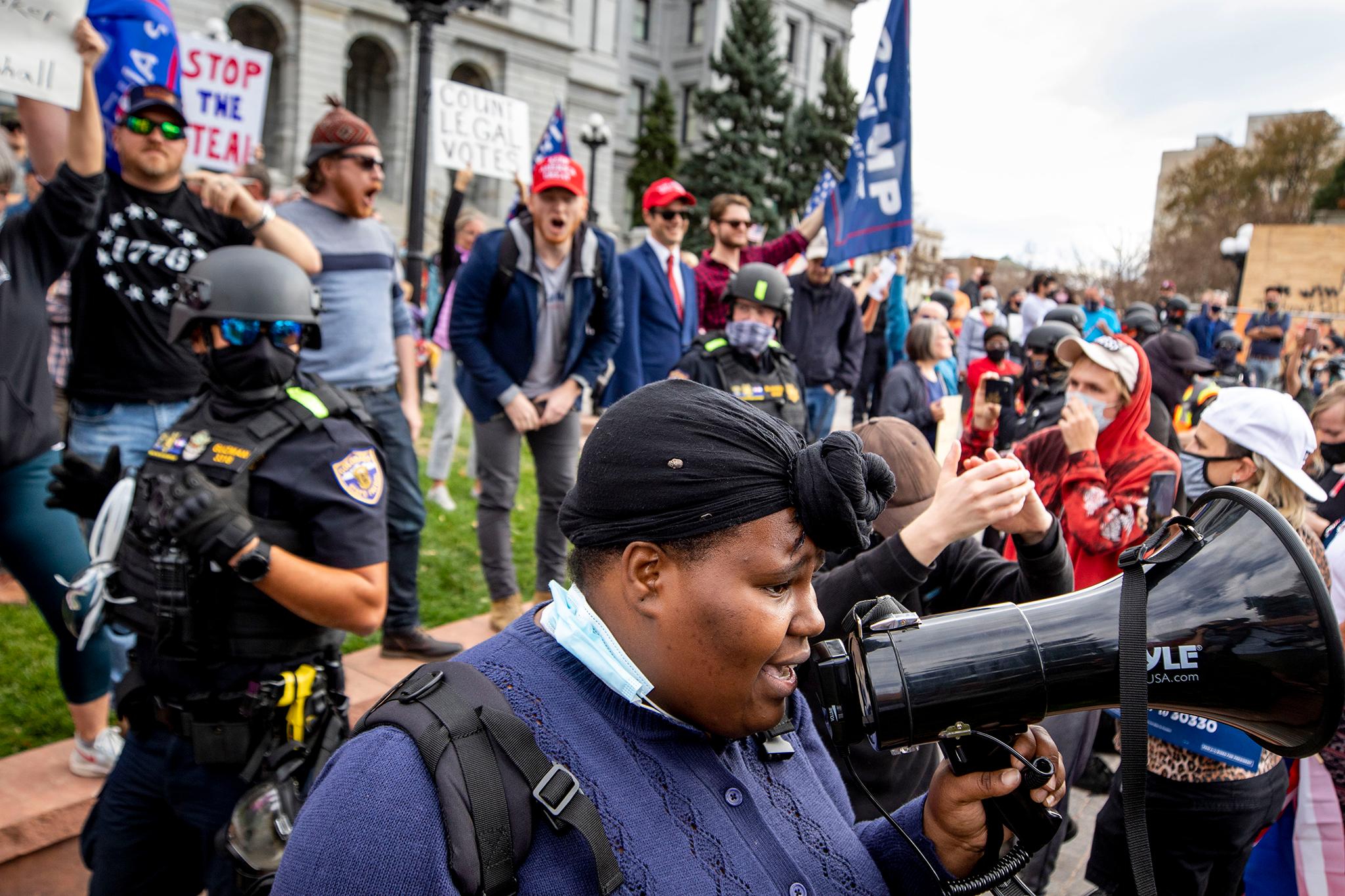 Iris Butler attempts to lead chants among supporters of Joe Biden as state police stand between them and supporters of Donald Trump at the Capitol. Nov. 7, 2020.