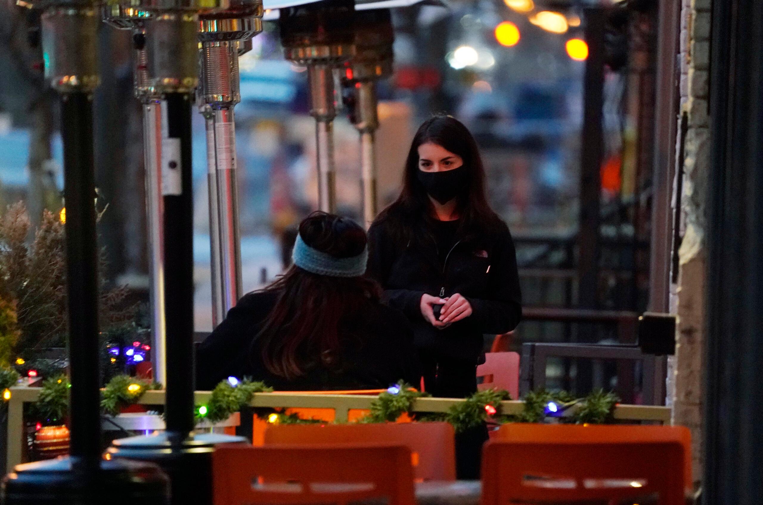 A waitperson wears a face mask.