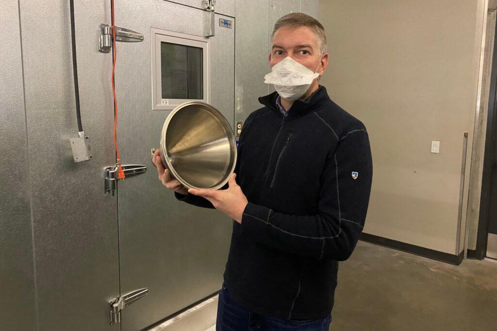 Colorado State University professor Jon Volckens stands next to the clean room he uses to count and size thousands of particles per minute. Researchers are using the instruments to measure emissions from singing, talking and playing instruments to see how COVID-19 particles spread.