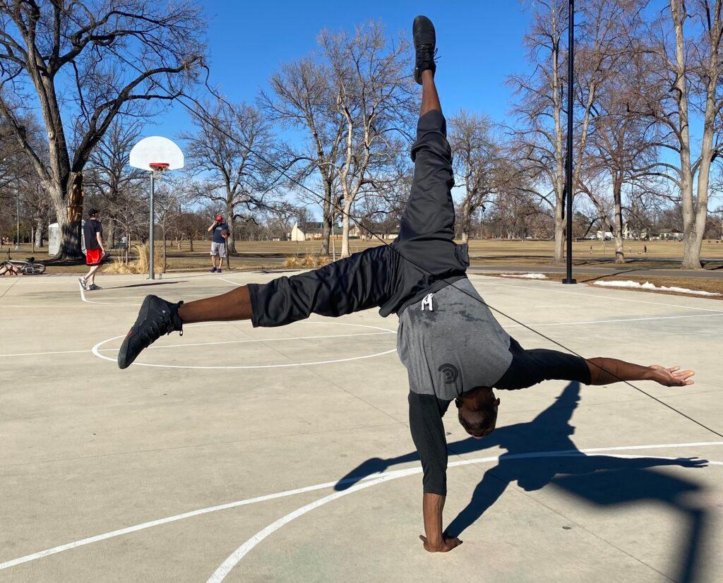 Dosh Simms does a handstand on one arm at the basketball courts in Washington Park on March 1, 2022.