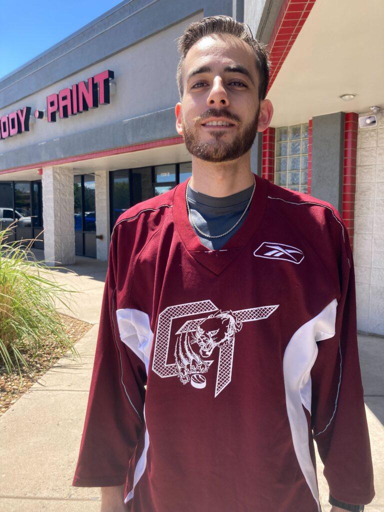 Taha Dakkak, owner of Tint My Ride, stands outside his shop donning his old high school roller hockey jersey. Dakkak is a 2011 graduate of Cherokee Trail High school in Aurora.