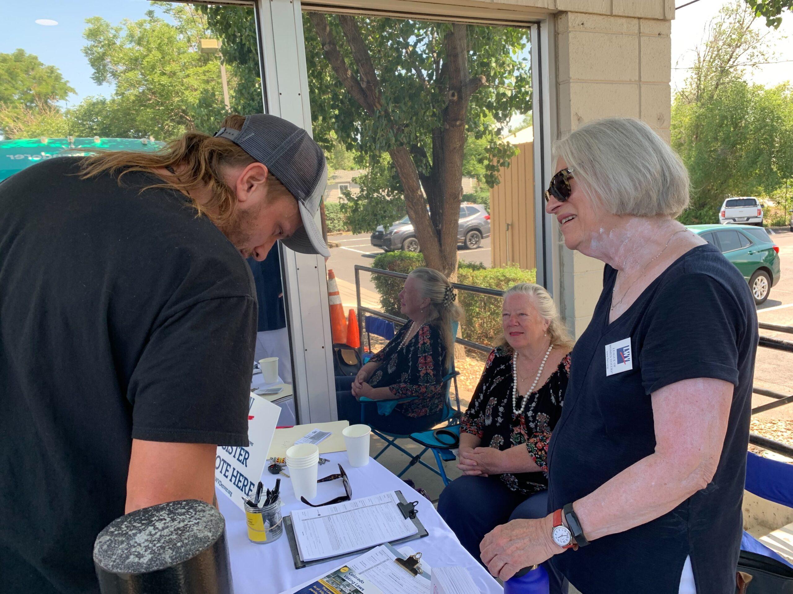 Elizabeth Bennett (sitting) and Anne Duncan (standing) are with the League of Women Voters and registered people to vote Thursday, Aug. 4 2022.
