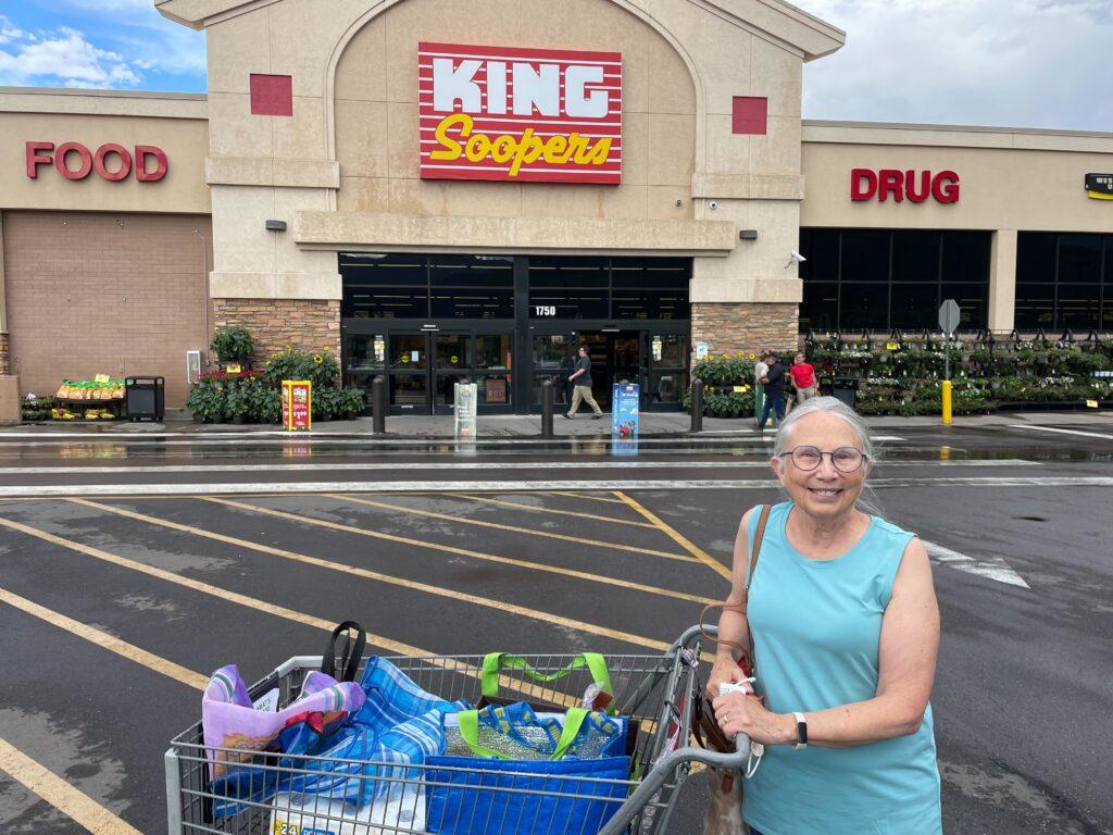 A woman stands in front of her shopping cart outside a King Soopers market in Colorado Springs.