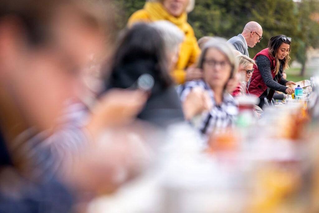 Guests gather for dinner at a long table dinner at City Park. Oct. 15, 2022.