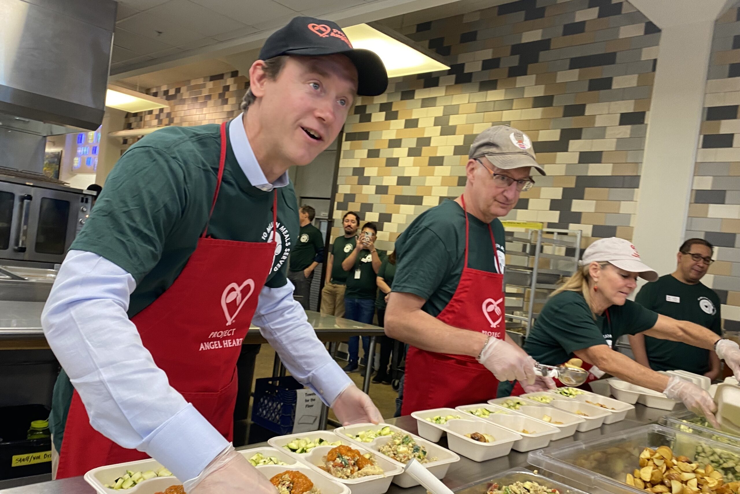 Denver mayor Mike Johnston stands alongside volunteers to make a meal