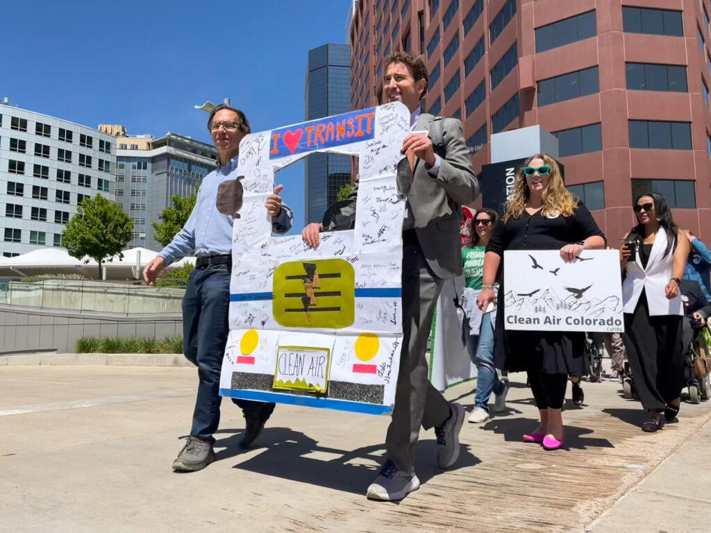 Public transit supporters carrying signs supporting air pollution bill that funds for RTD.