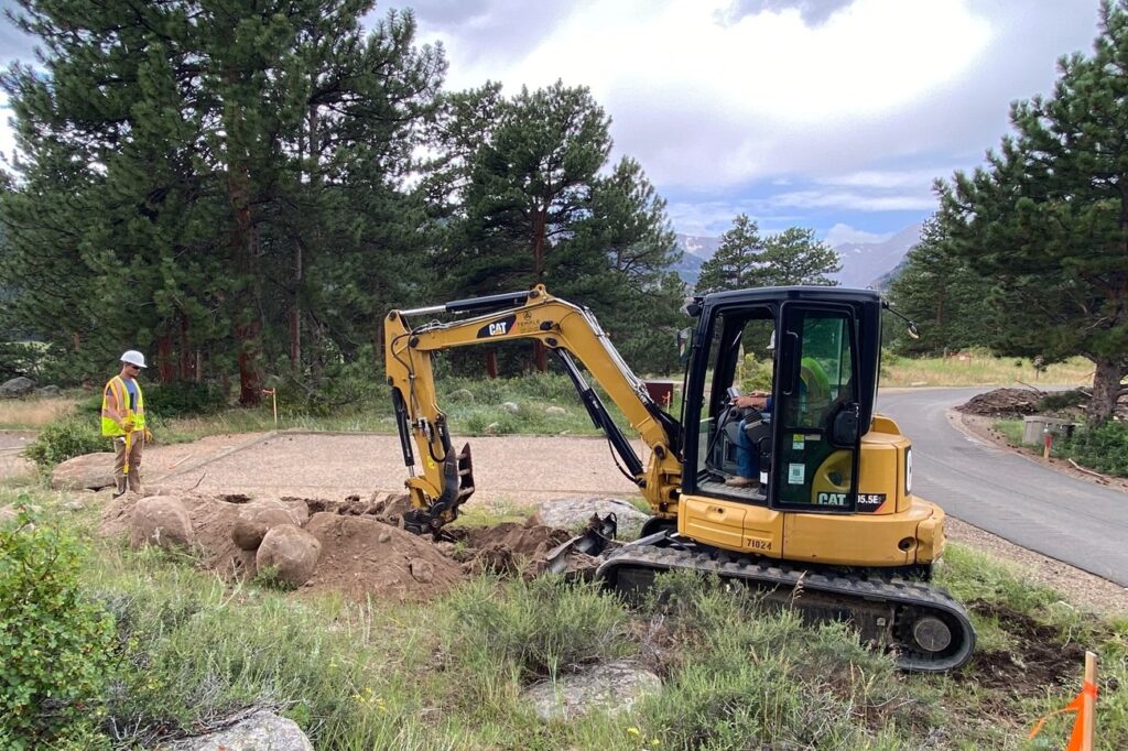 Construction workers digging a trench near an existing campsite in Moraine Park Campground for new electrical hook-ups.