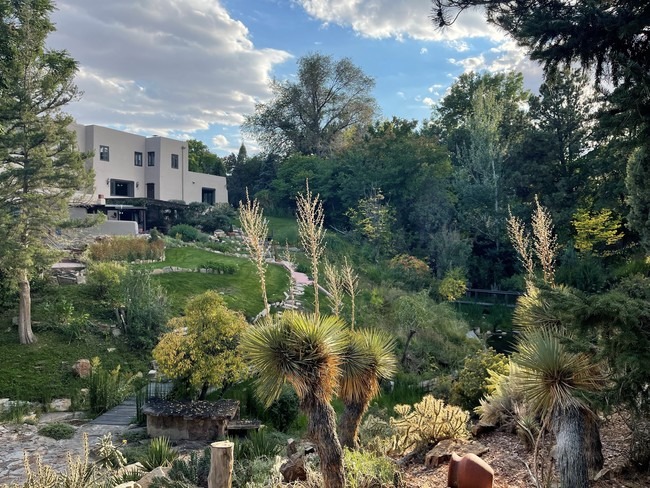 A large, partially xeric garden with an adobe-style home in Pueblo