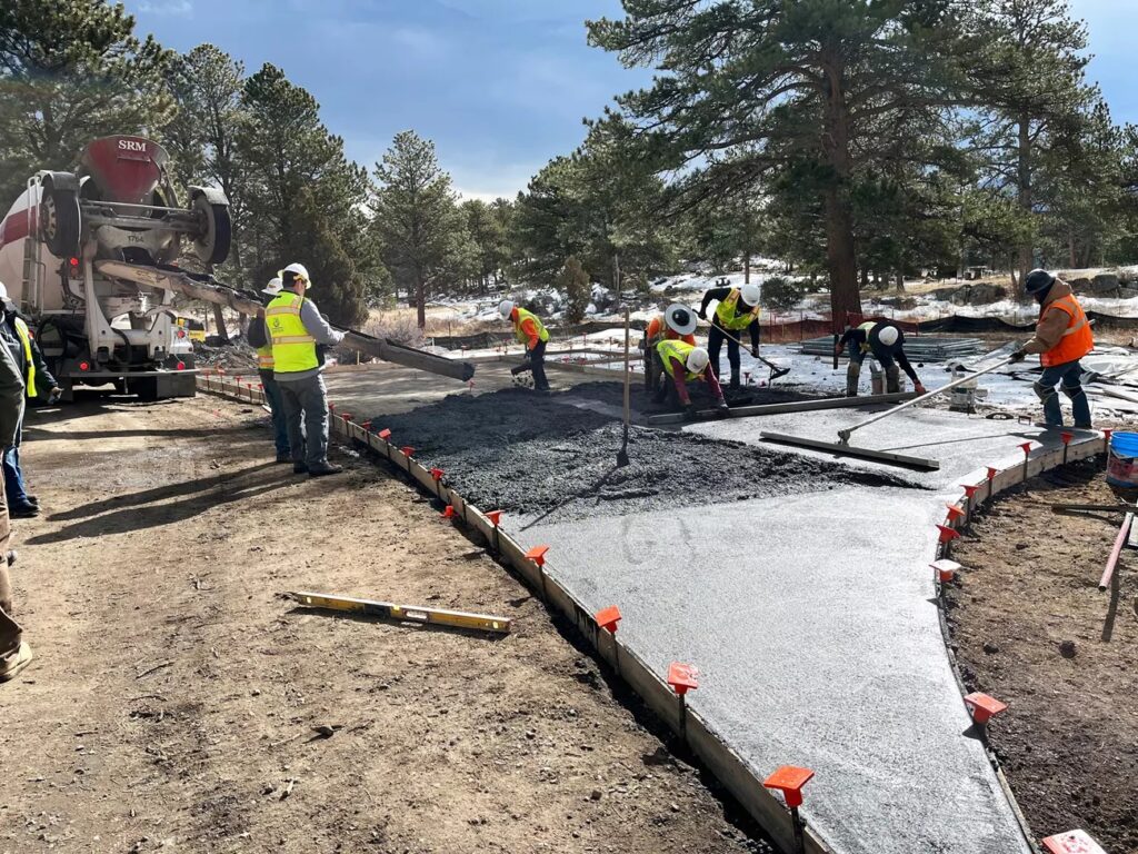 Workers pouring and smoothing concrete for a new campsite in Moraine Park Campground.