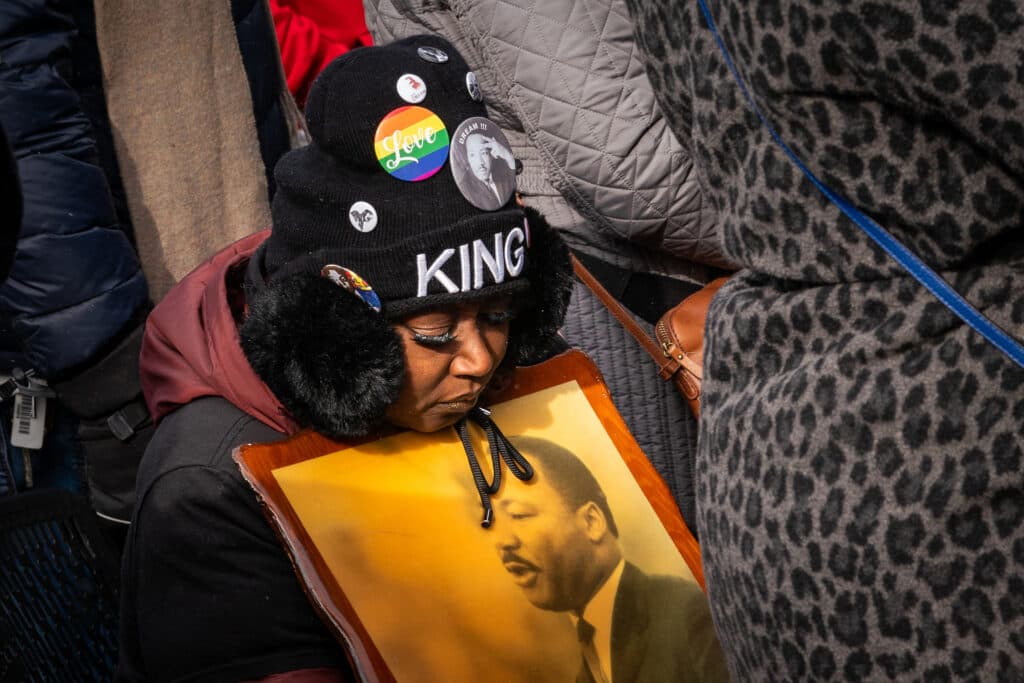 A MARADE PARTICIPANT RESTS WITH A PHOTO OF MARTIN LUTHER KING
