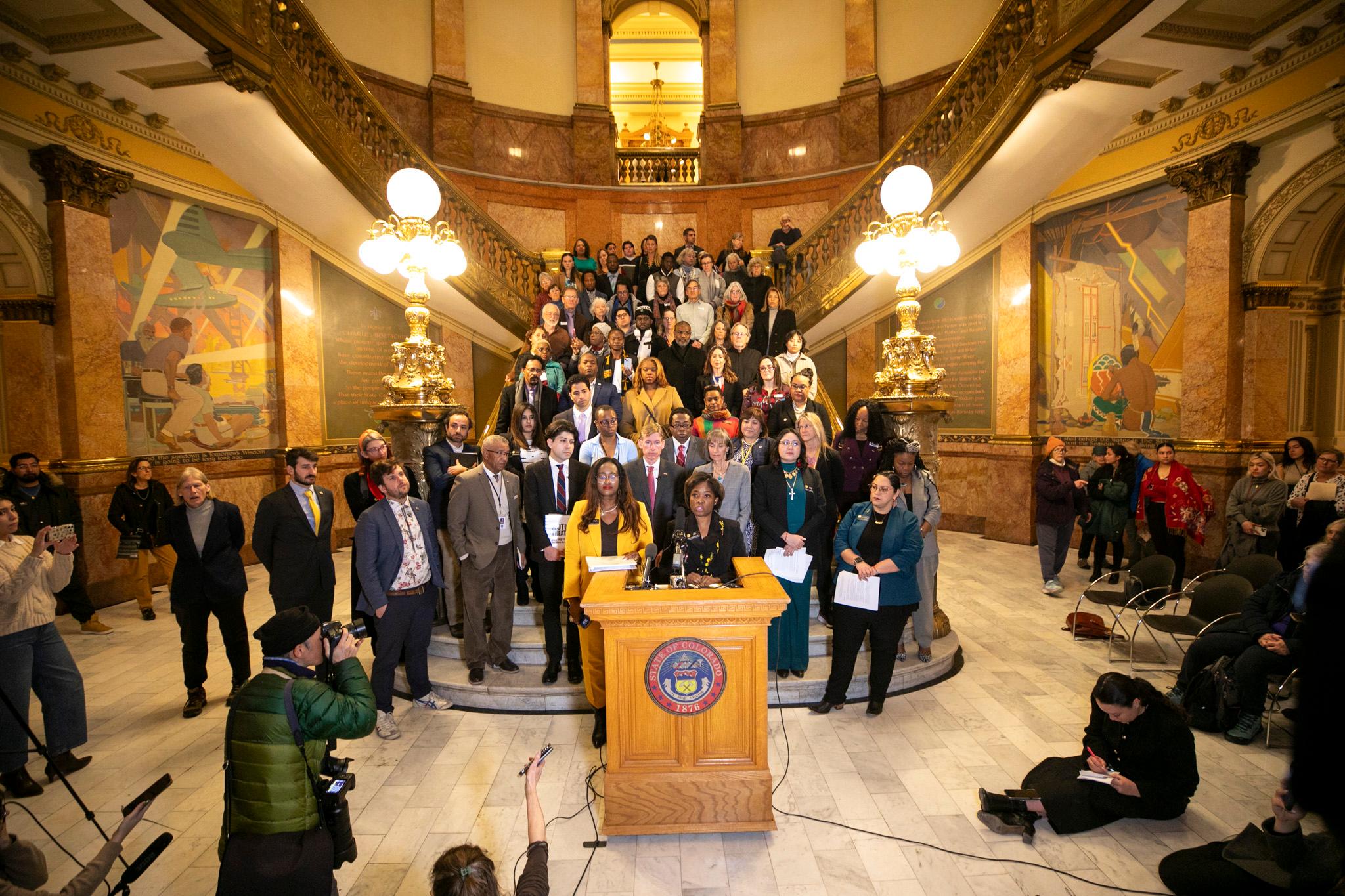 Several lawmakers hold a press conference on steps inside the Colorado State Capitol