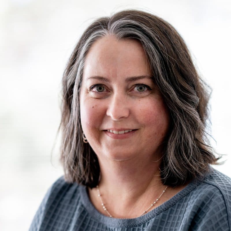Woman with brown and gray hair and a blue top