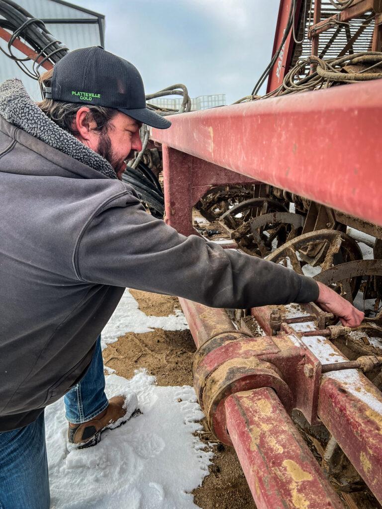 A man who farms sugar beets, among other crops, shows off the blades of a sugar beet harvester.