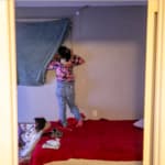 An immigrant from Venezuela peeks out of a window to check for police.