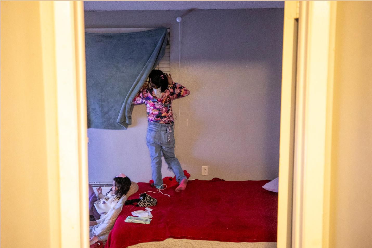 An immigrant from Venezuela peeks out of a window to check for police.