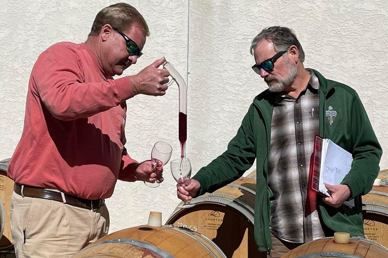 two people taste wine from barrels