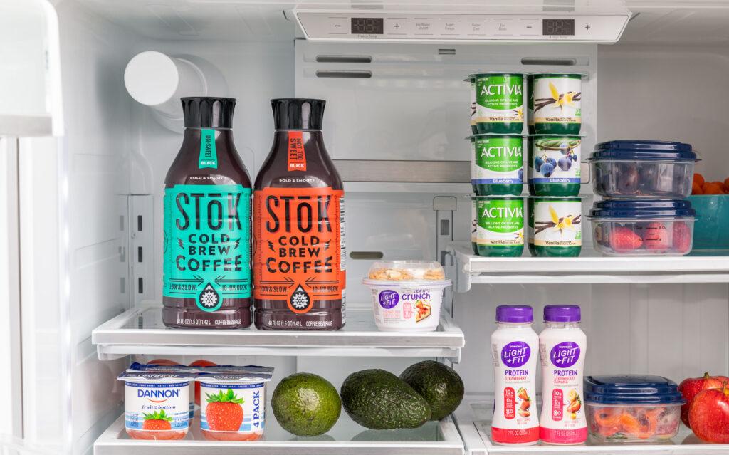 An open refrigerator with beverages and yogurt