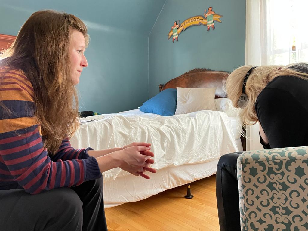 Woman looks empathetically at patient who is holding herself mid therapy session.