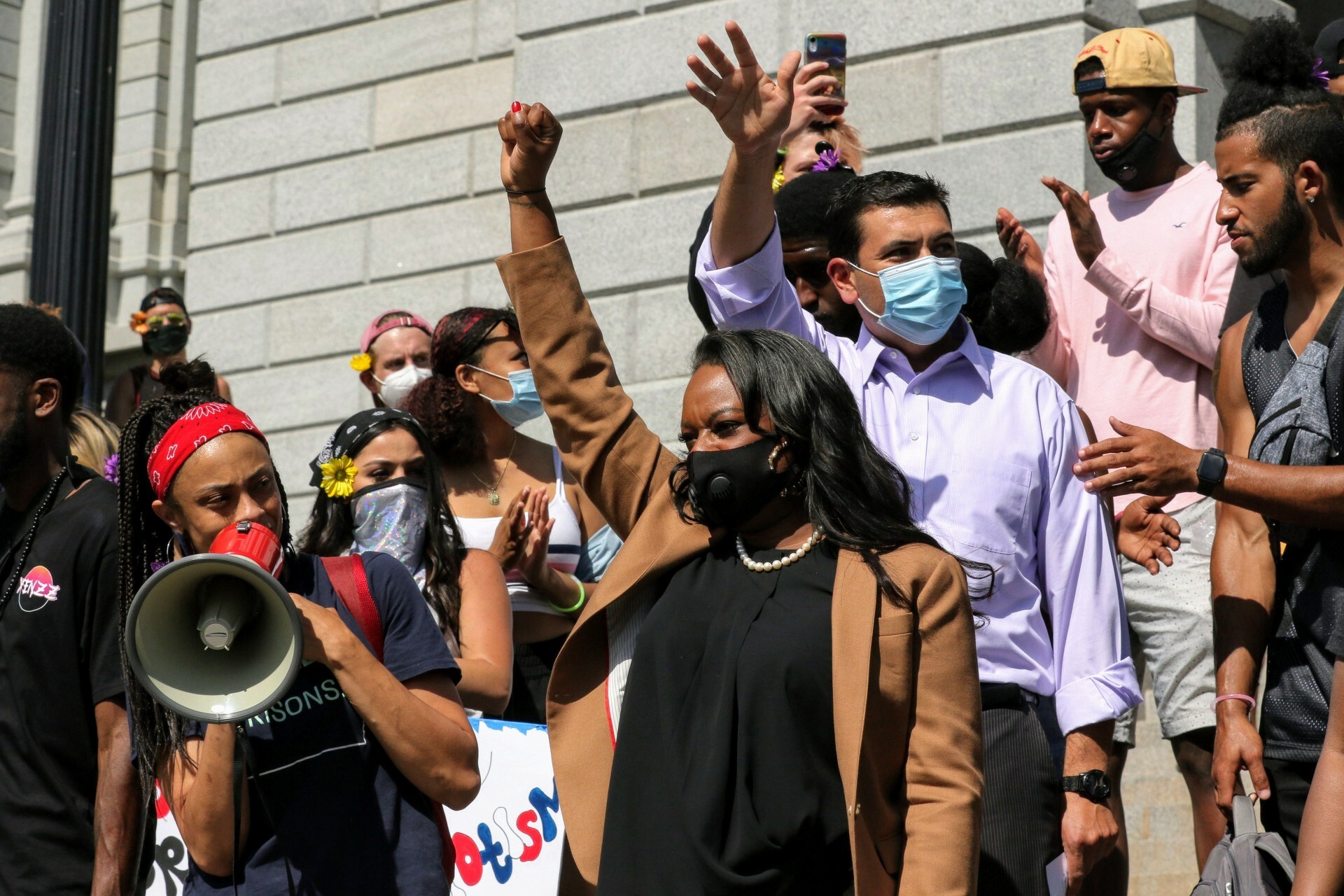 Rep. Herod, in a black COVID mask, stands in a crowd of people on the steps of the capitol.