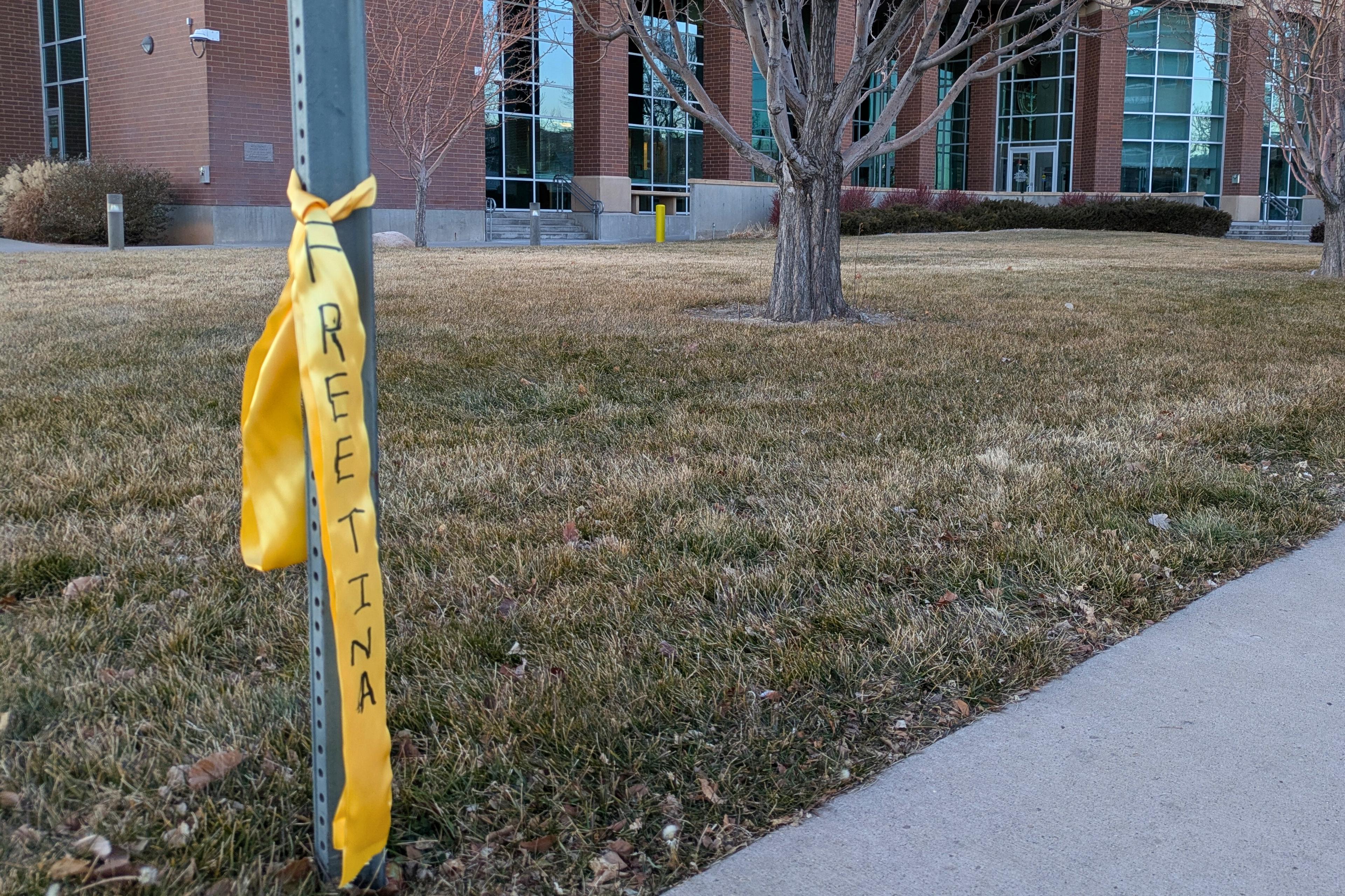 A yellow ribbon tied around a metal pole