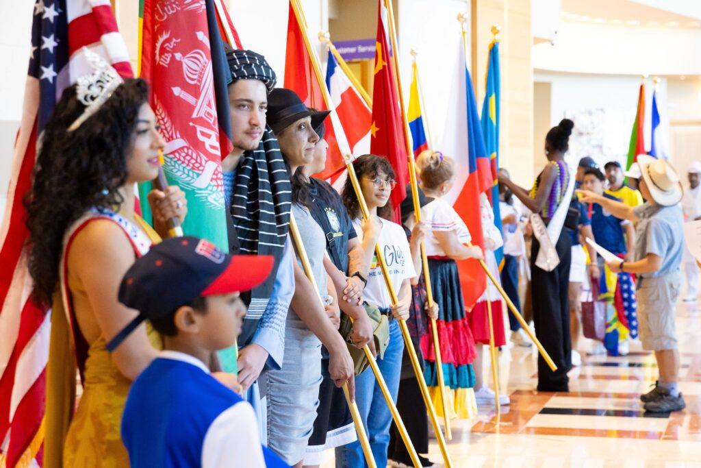 group of people from different cultures standing with flags inside large building