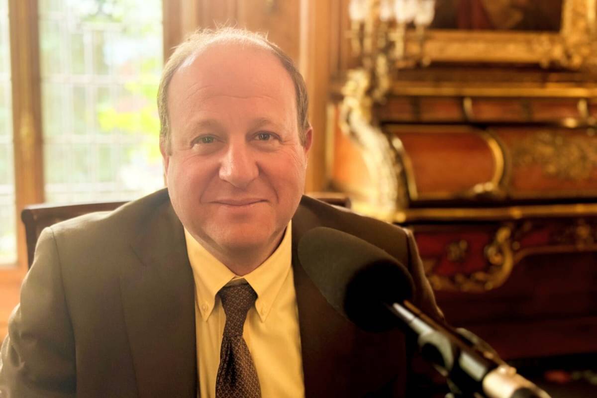 Governor Jared Polis in front of a mic during an interview