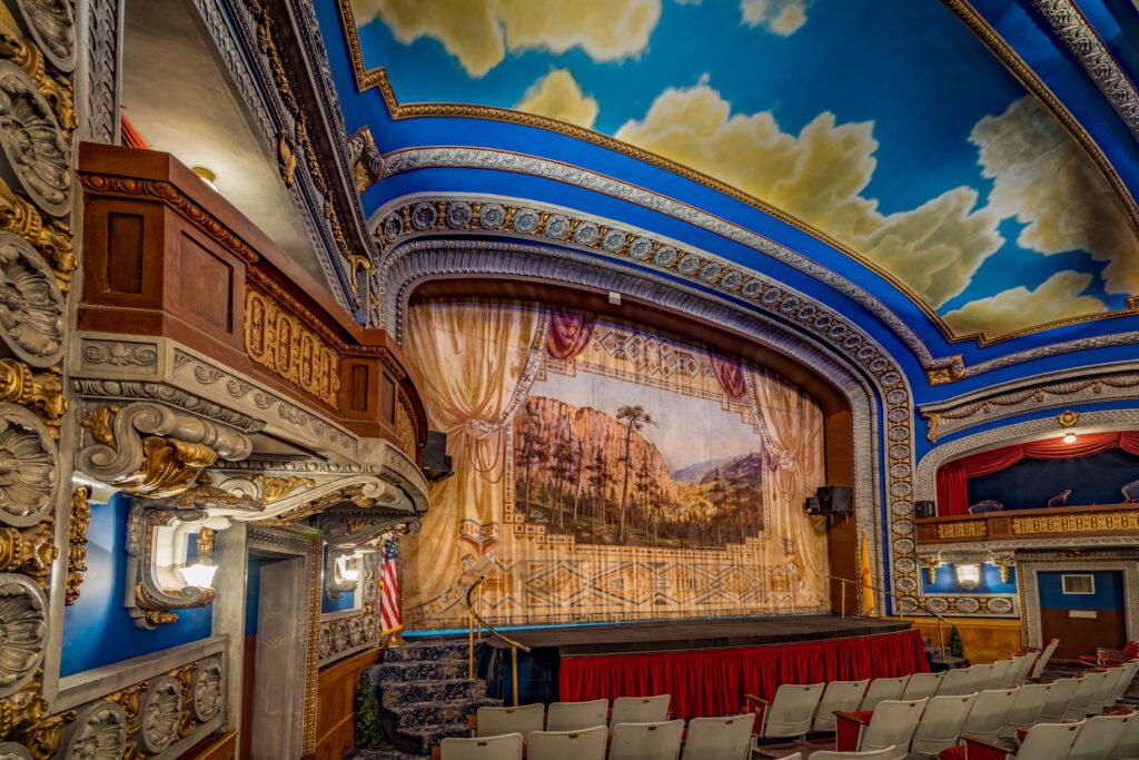 interior of and ornate theater including an colorful stage, proscenium and decor