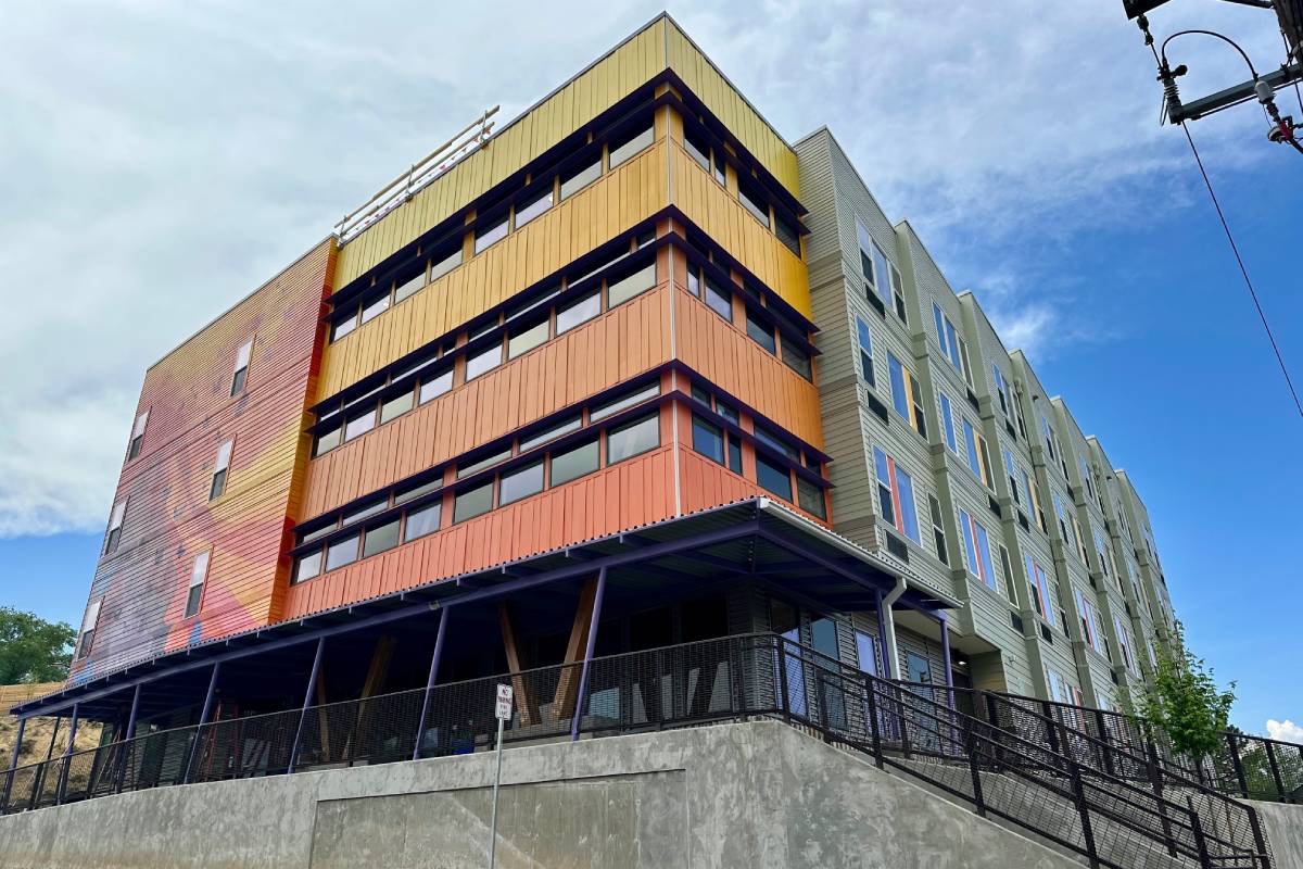 An apartment building is shown with one side colorfully painted in yellow and orange.