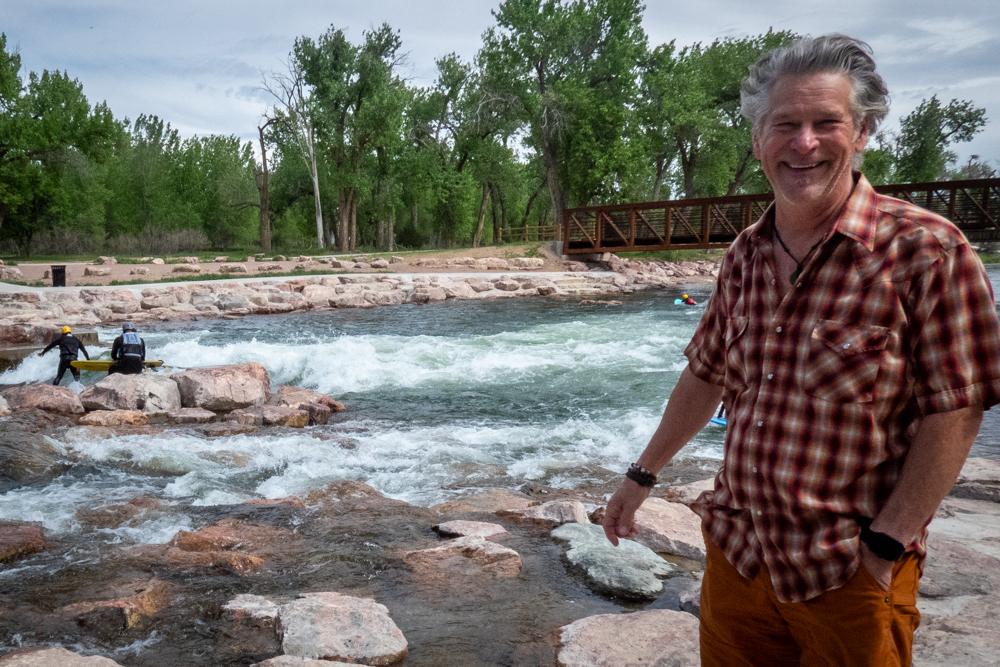 a smiling man stand near the river