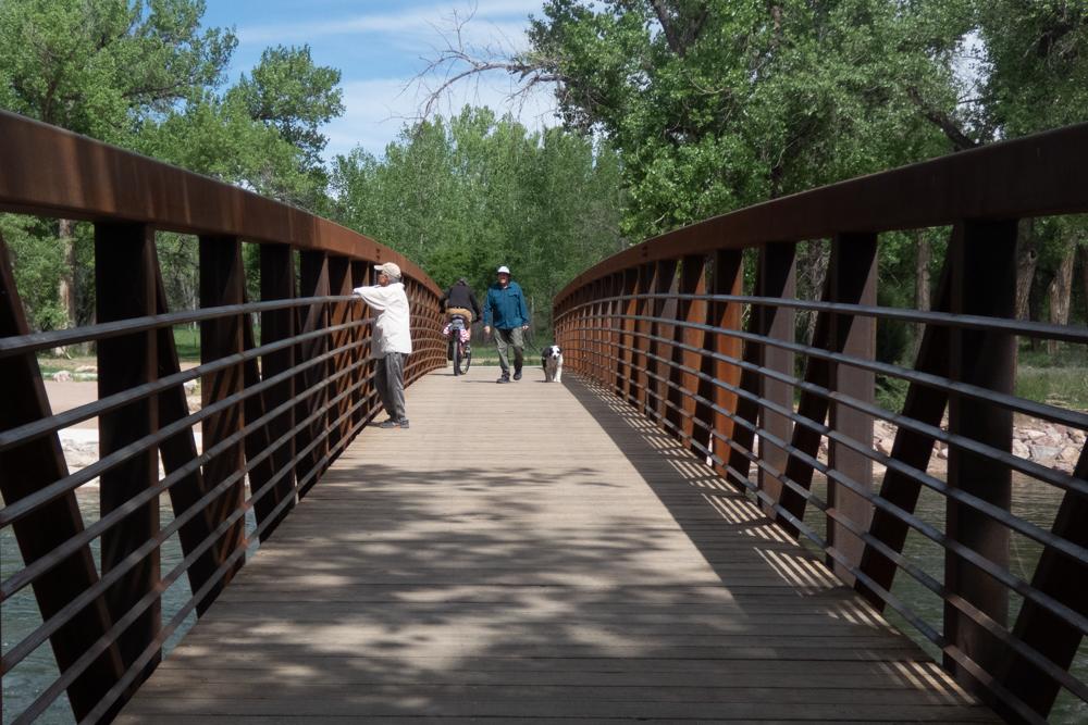 pedestrians and a bike rider walk on a bridge