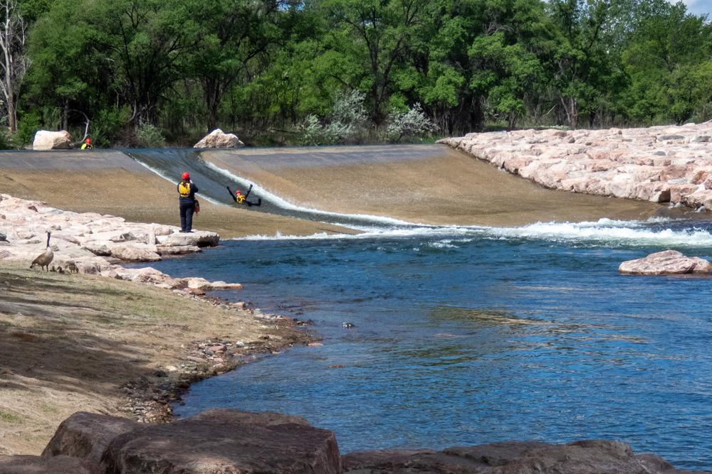 a person rides down a chute on a spillway in the river