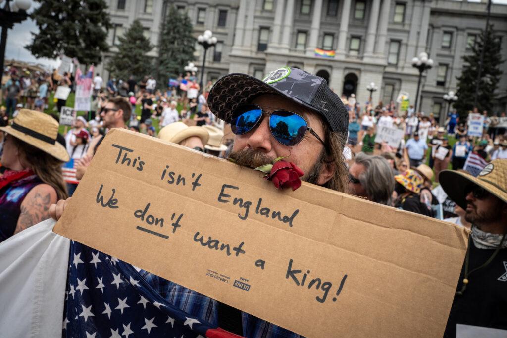 No Kings protest: Charles Clements carries a rose and a sign saying “we don’t want a king!”