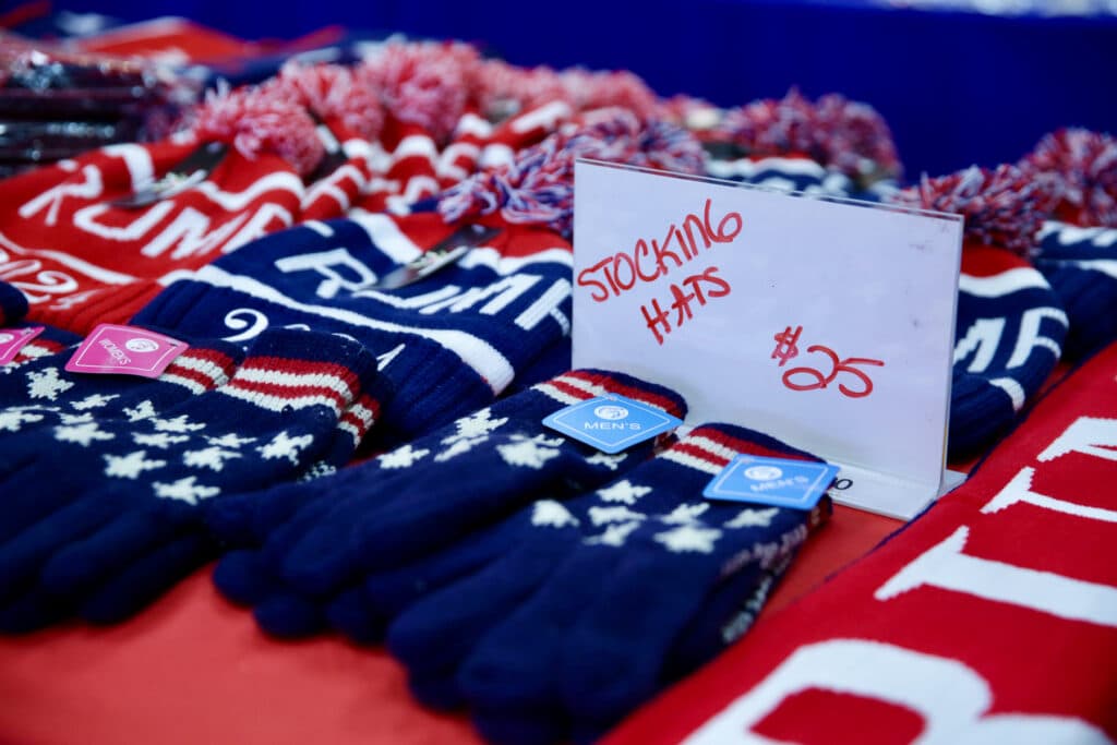 A close-up of a table strewn with winter hats and gloves with American flag designs is shown.