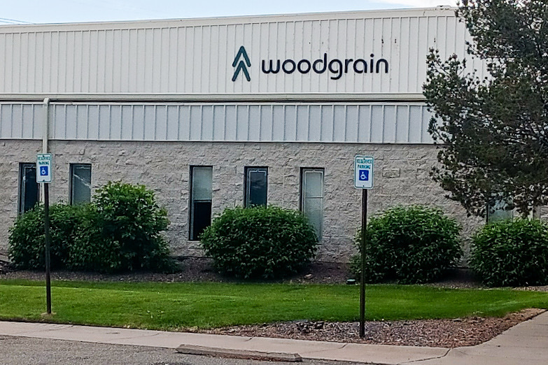 A warehouse building taken from the street outside, with some trees and grass in front